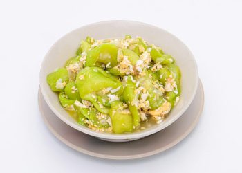 stir-fried zucchini with eggs in a white dish on a white isolated background. Thai food. Top view.