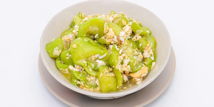 stir-fried zucchini with eggs in a white dish on a white isolated background. Thai food. Top view.
