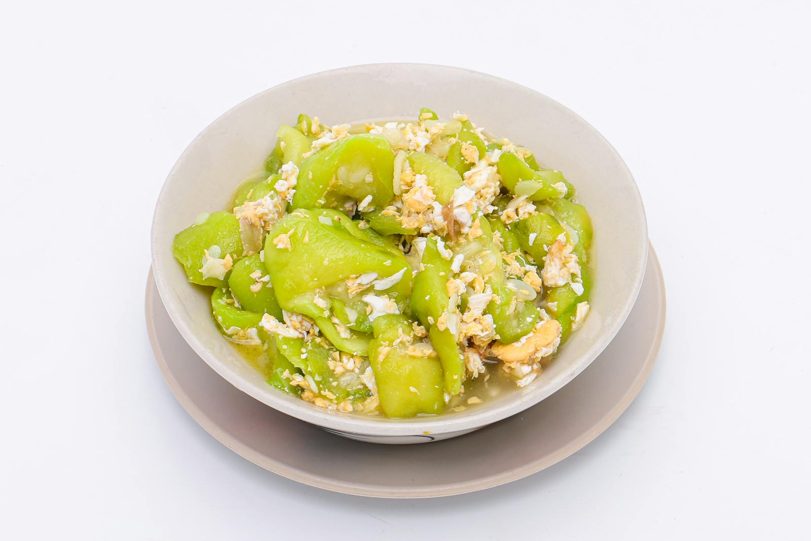 stir-fried zucchini with eggs in a white dish on a white isolated background. Thai food. Top view.