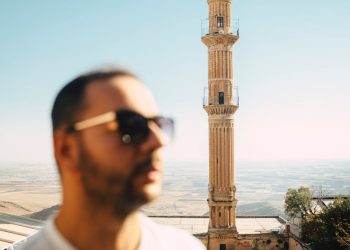 A man enjoying a sunny day with a historic minaret in Mardin city, Turkey.