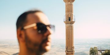 A man enjoying a sunny day with a historic minaret in Mardin city, Turkey.