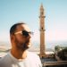 A man enjoying a sunny day with a historic minaret in Mardin city, Turkey.