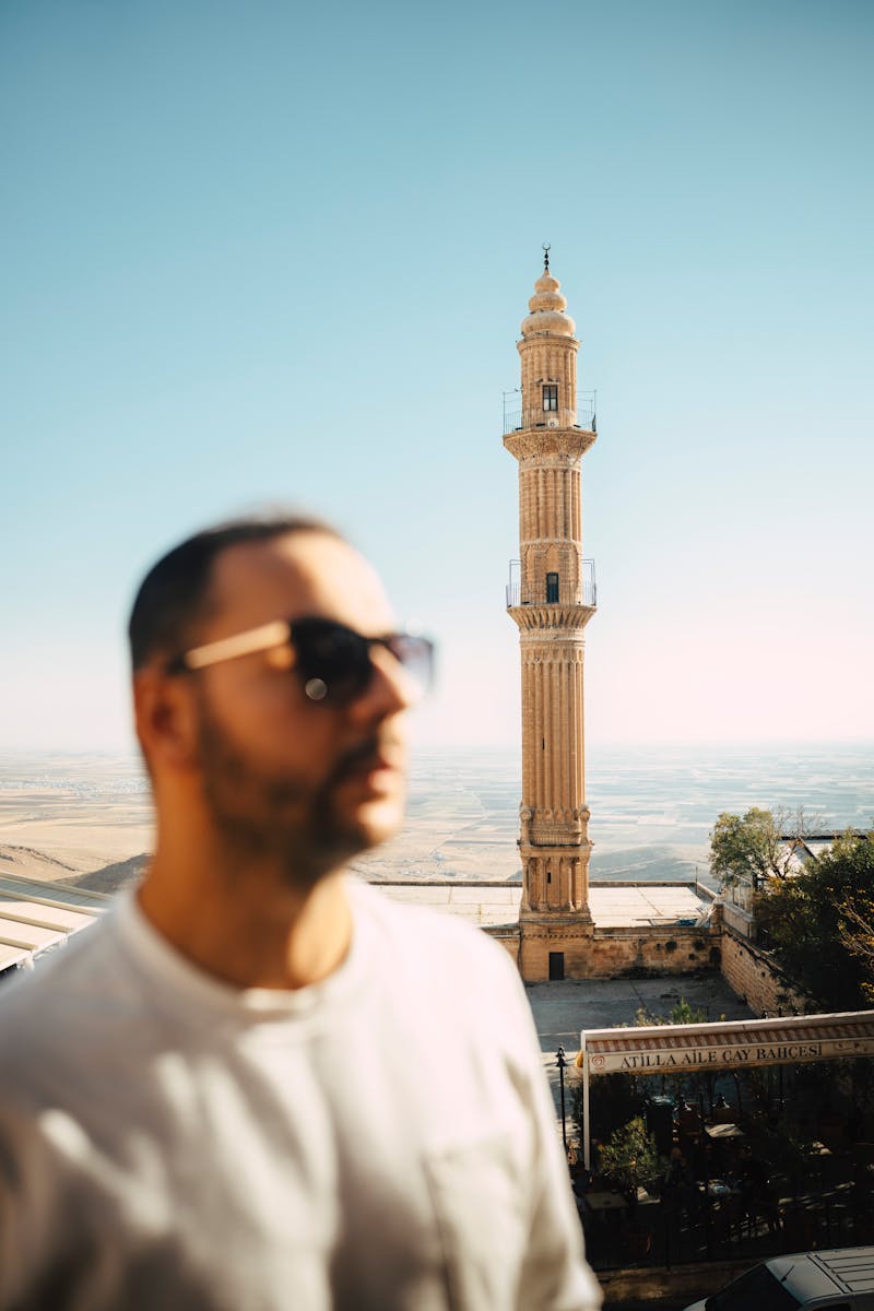 A man enjoying a sunny day with a historic minaret in Mardin city, Turkey.