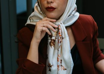 Stylish woman wearing a hijab and sunglasses enjoys coffee in Istanbul café.