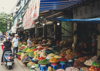 Person in Scooter in Front of Vegetables