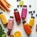 Colorful Bottles with Smoothies Beside Carrots, Ginger, Leaves and Berries