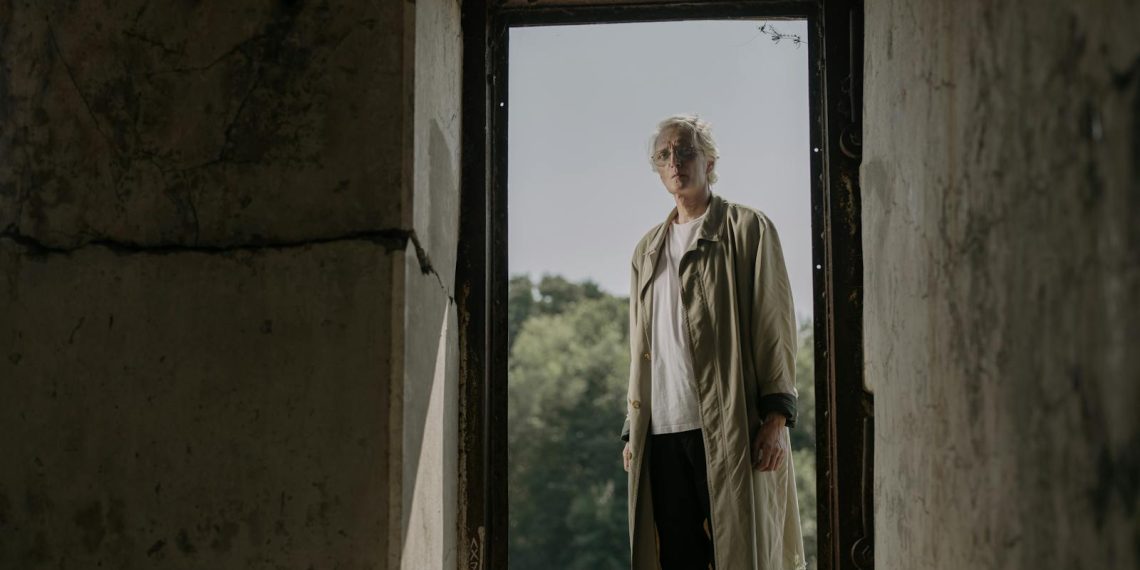 Senior Man in White Shirt and Beige Trench Coat Standing on a Doorway