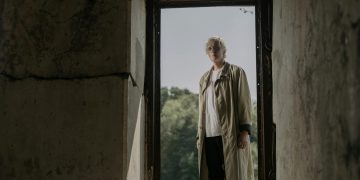 Senior Man in White Shirt and Beige Trench Coat Standing on a Doorway