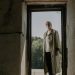 Senior Man in White Shirt and Beige Trench Coat Standing on a Doorway
