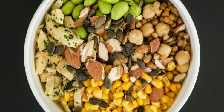 Top view of bowl full of healthy tasty fresh corn and beans prepared for cooking salad on black background