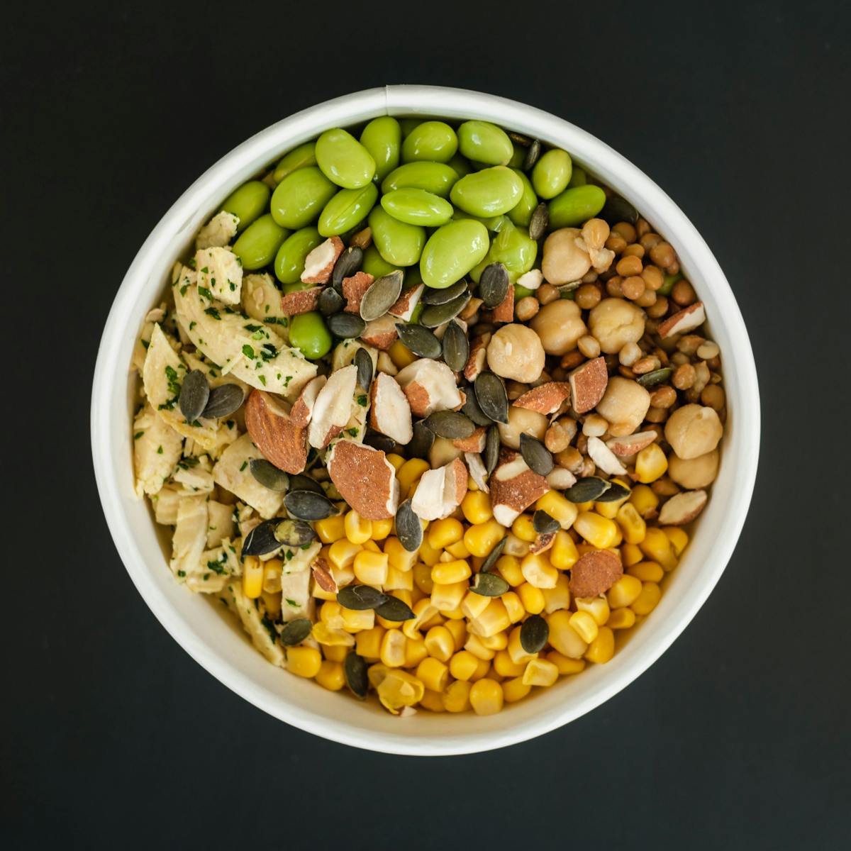 Top view of bowl full of healthy tasty fresh corn and beans prepared for cooking salad on black background