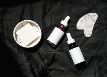 Brown Glass Bottles on Black Textile Beside Gua Sha and Soap