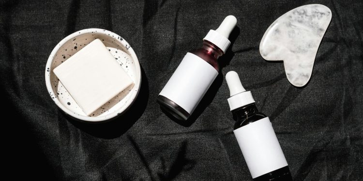 Brown Glass Bottles on Black Textile Beside Gua Sha and Soap